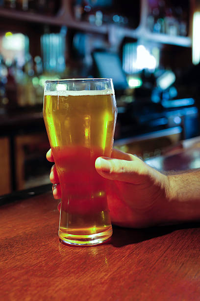 istock Hand Holding Beer Glass on a Pub Bar 183035076