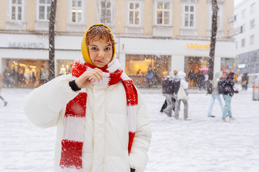 Positive portrait teenage girl in snowfall cityscape