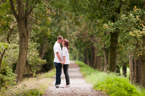 young couple kissing on a forest way