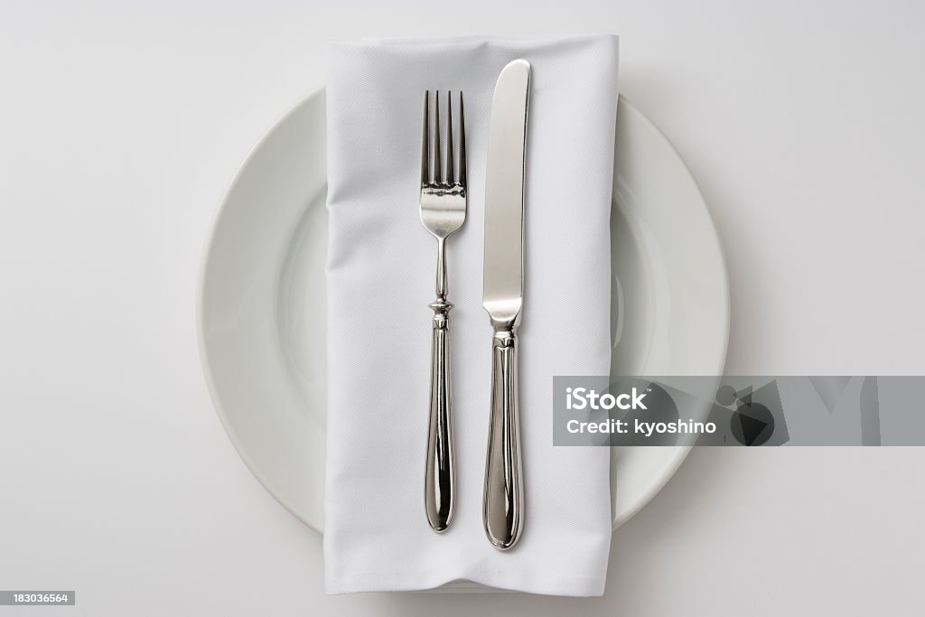 Isolated shot of plate and cutlery on white background Overhead shot of dinner plates and cutlery with white napkin isolated on white background. Napkin Stock Photo