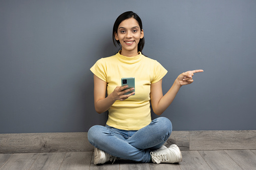 Young woman using phone on wood floor