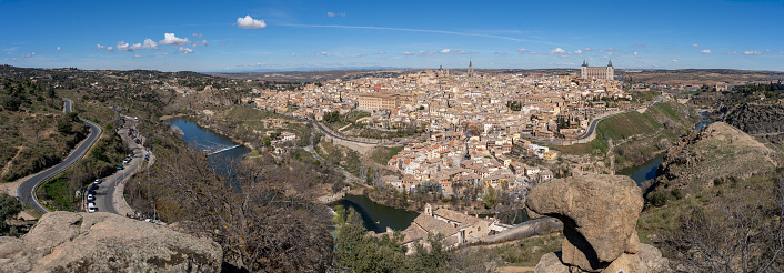 Panoramic view of the historic city of Toledo with the passage of the Tagus River from the Moorish King's Stone, well-known viewpoint of the city on a sunny day. UNESCO World Heritage Site. Spanish tourism concept
