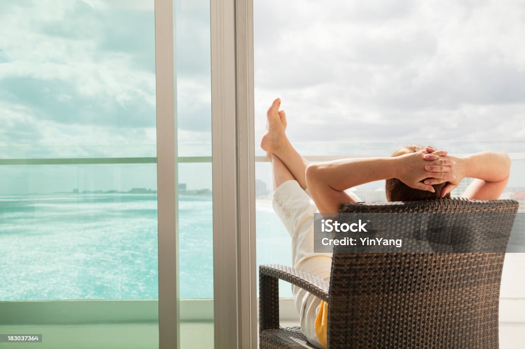 Relaxing in Hotel Balcony with Scenic Beach and Sea Views "Subject: An adult woman on vacation, relaxing in the balcony of the hotel room in a beach resort.Location: Cancun, Mexico." Relaxation Stock Photo