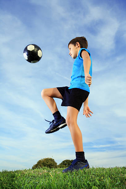 istock Boy playing football on meadow. 183037518