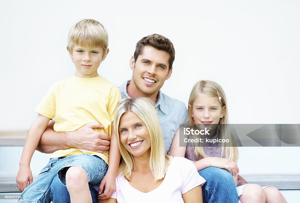 Medio de la pareja feliz con sus hijos de estar - Foto de stock de Abrazar libre de derechos