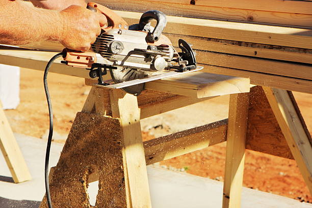 Saw Cutting Construction Lumber Plank Carpenter uses worm-drive circular saw to cut lumber plank at construction work site.  Sedona, Arizona, 2010. sawhorse stock pictures, royalty-free photos & images