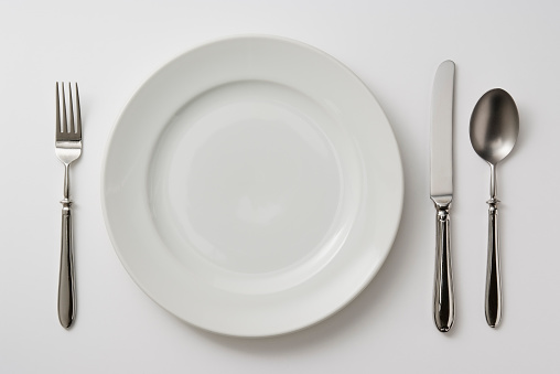 Isolated shot of plate with cutlery on white background