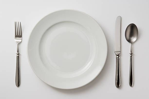 Isolated shot of plate with cutlery on white background Close-up shot of dinner plate with cutlery isolated on white background. eating utensil stock pictures, royalty-free photos & images