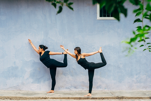 Two Hispanic women in dancer pose on the street in the daytime. Concept of yoga.