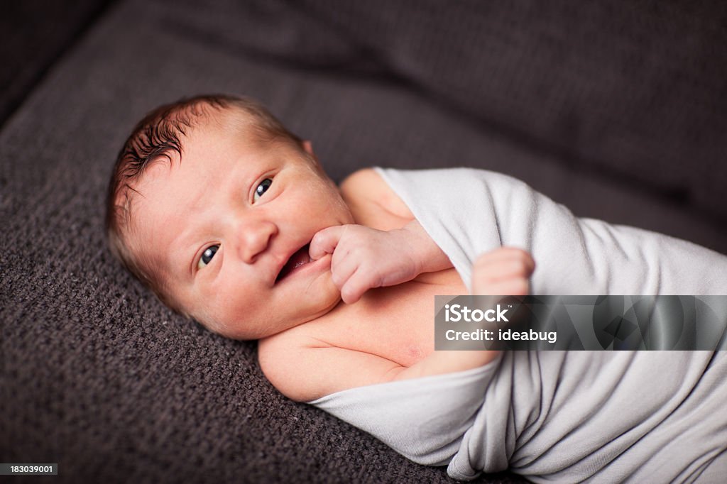 Envuelto en una manta de bebé recién nacido, poner un dedo en la boca - Foto de stock de Poner un dedo en la boca libre de derechos