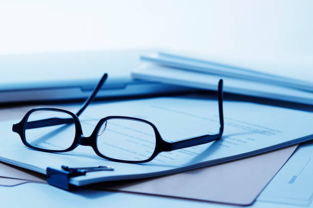 istock Blue tinted image of stacked document with glasses 183039470