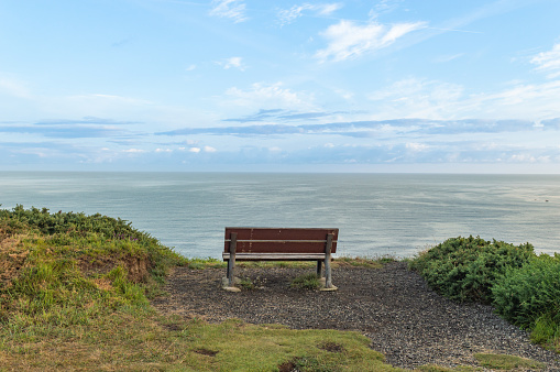 sea landscape with wooden bench and cloudy sky