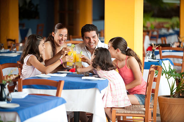 familia en un restaurante - los niños y los padres brindis bebidas mientras almuerza fotografías e imágenes de stock