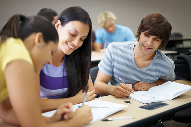 istock Happy young college friends studying together in classroom 183040358