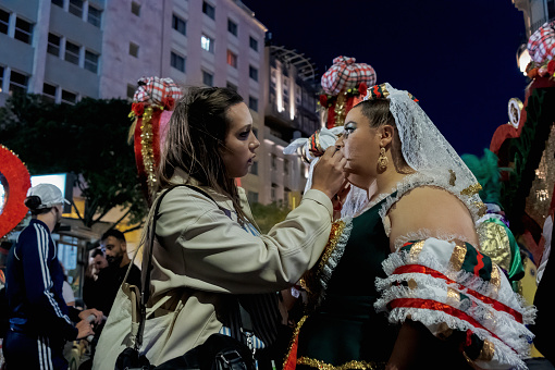Lisbon, Portugal - June 12, 2023: A woman dressed in tradtional folklore costume, gets final make-up retouches before parading in Lisbon downtown, during this city celebrations of the Popular Saints.