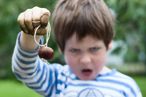 A five year old boy with filthy hands playing conkers. Focus on hand. UK