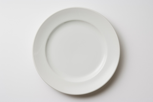 Overhead shot of white dinner plate on white background.