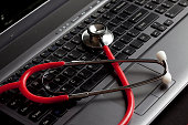 Red stethoscope on top of black keyboard