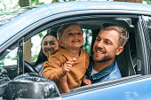 Smiling, having fun. Family of father, mother and little son are sitting in the modern car