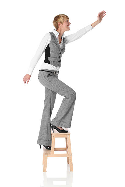 isolated young businesswoman on a ladder on white background studio
