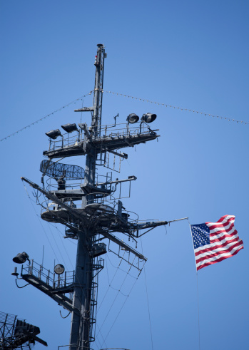 The deck of a large ship at in the ocean with cell towers United States of America Flag Blowing in the Wind