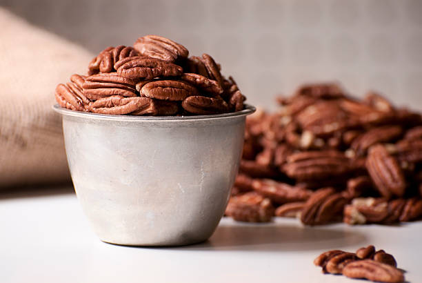 Pecans over-filliing a measuring cup with more pecans in the background.Similar images: