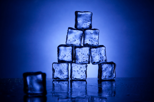 Pyramid of sweating ice cubes with one piece out of place.