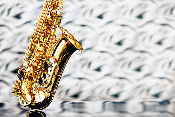 Close up of saxophone on reflective perspex with unfocussed background Close up of shiny golden sax on shiny perspex against an out-of-focus black and white background. Shot with Canon EOS 1Ds Mark III. perspex stock pictures, royalty-free photos & images