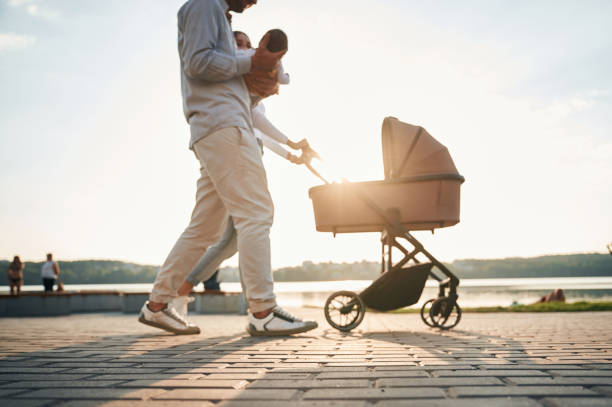 istock Side view. A young couple with a baby pram is walking together 1830451261