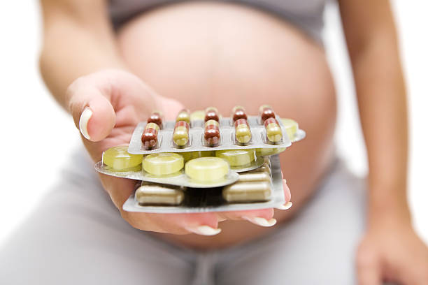 Close-up of a pregnant woman holding packages of pills stock photo