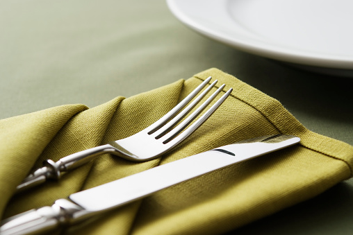 Close-up of a table setting with fork, knife and lime green napkin with copy space,