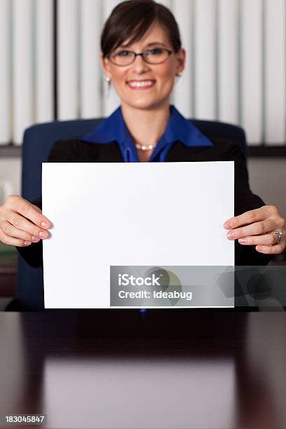 Happy Young Business Woman Sitting At Desk Holding Blank Paper Stock Photo - Download Image Now