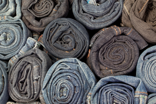 Rolled up blue denim jeans image.  Full frame textile industry background.