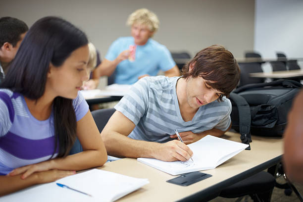 istock Young male writing something and his classmate in classroom 183046810
