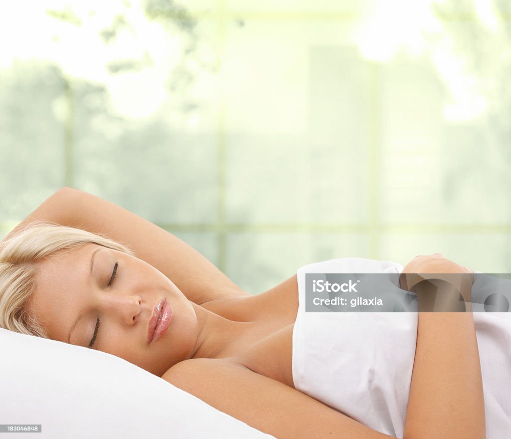 Sleeping beauty. Beautiful blond woman covered with sheets during sleep.Isolated version: 20-24 Years Stock Photo