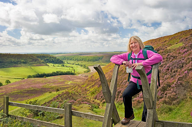 Hiker on style Senior female hiker crossing a stile in the English countryside. Shallow depth of field with focus on hiker. life stile stock pictures, royalty-free photos & images