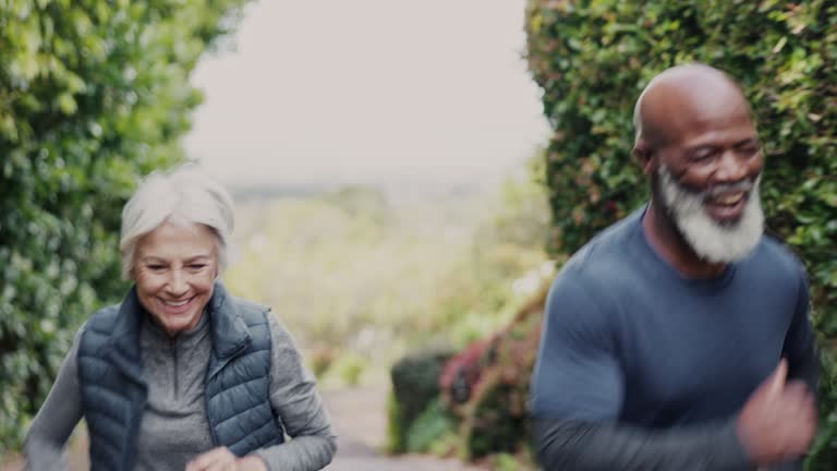 Senior, man and woman with high five for workout, running and exercise outdoor in forest with happiness. Elderly, people and training with smile for performance, teamwork and motivation in nature