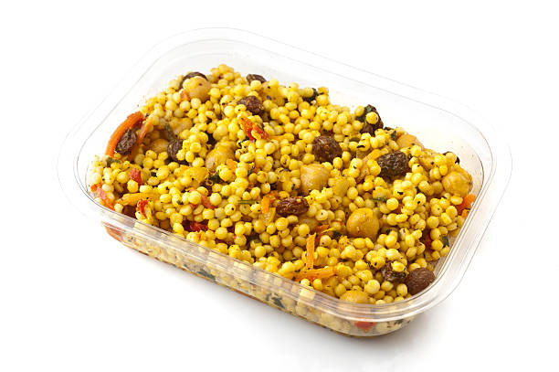 Plastic container full of israeli couscous (pearls couscous) salad on white background