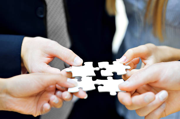 Close up of hands holding puzzle pieces Close up of four business people' hands with puzzle big idea stock pictures, royalty-free photos & images