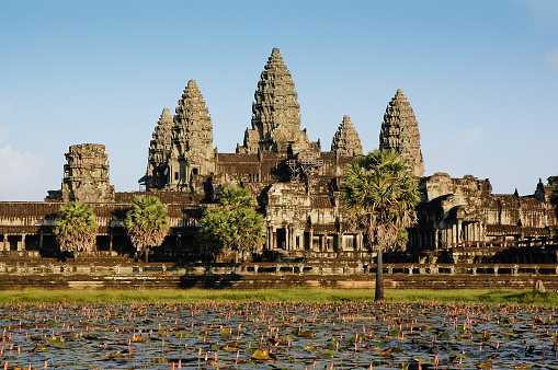 Angkor Wat, Cambodia – August 04, 2022: The temple towers of the largest religious temple complex Angkor Wat in Cambodia, with tourists visiting it on a sunny day