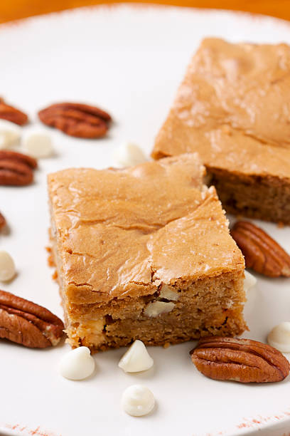 Blondies White chocolate brownies called blondies nestled among white chocolate chips and pecans. blondy stock pictures, royalty-free photos & images