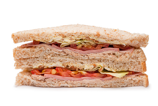 Sandwich with ham, egg salad, tuna, bacon, tomato, lettuce in whole wheat bread on isolated white background