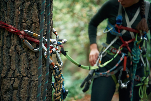 Close up particle view. Man is doing climbing in the forest by use of safety equipment.