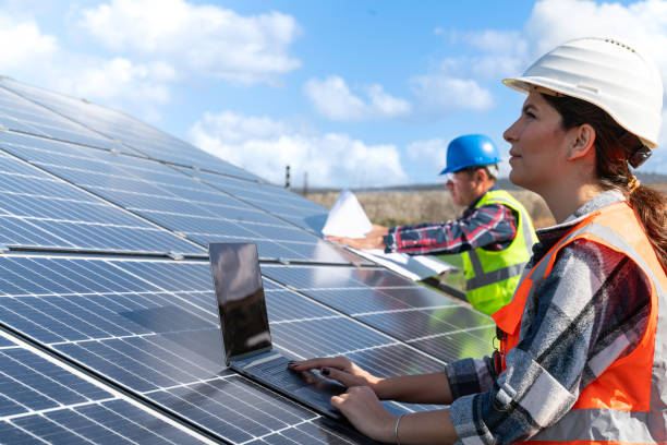 istock Young engineer inspect installation of solar panels installed check  with blueprint on the field, with recording inspection data on pc. 1830509535