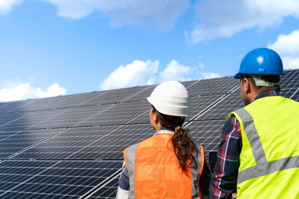 istock Young engineer inspect installation of solar panels installed check  with blueprint on the field, with recording inspection data on pc. 1830510072