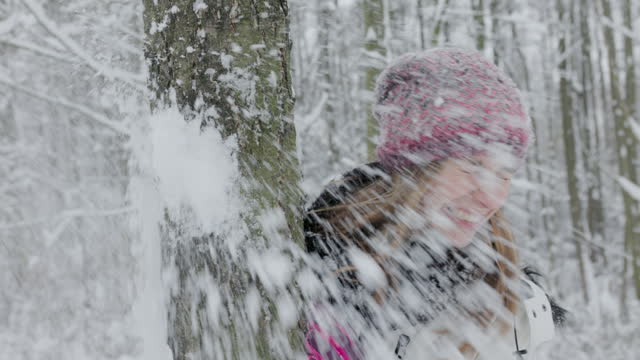 Teenager girl having a snowball fight in forest