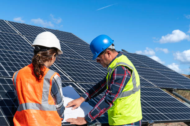 istock Young engineer inspect installation of solar panels installed check  with blueprint on the field, with recording inspection data on pc. 1830510820