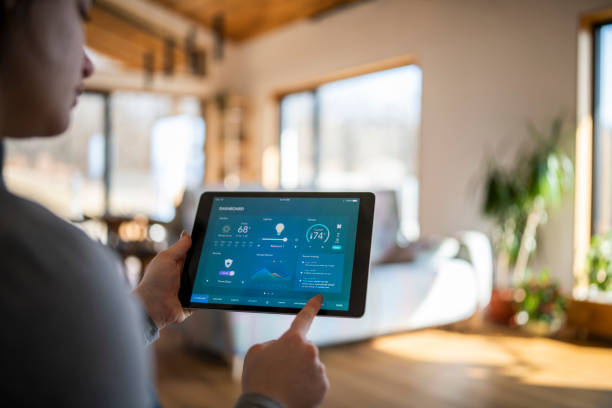 Woman using tablet with smart home control functions. Young woman at home using tablet with smart home control functions. home automation stock pictures, royalty-free photos & images