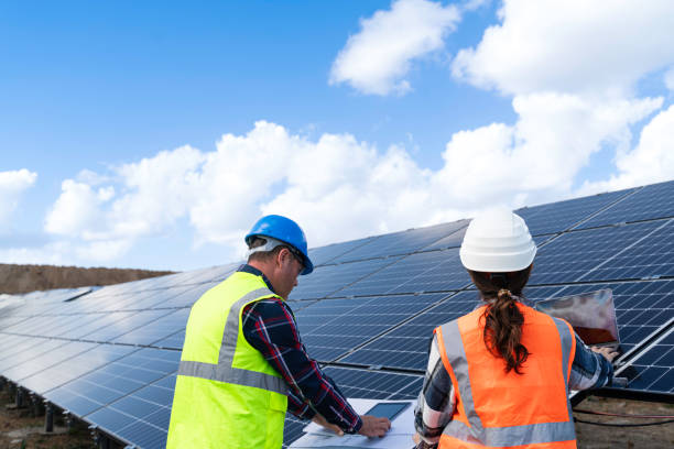 istock Young engineer inspect installation of solar panels installed check  with blueprint on the field, with recording inspection data on pc. 1830512239