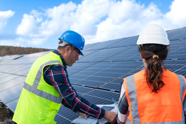 istock Young engineer inspect installation of solar panels installed check  with blueprint on the field, with recording inspection data on pc. 1830512779
